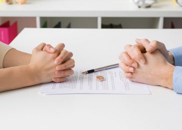 close photo of a couple sitting across from one another with divorce papers